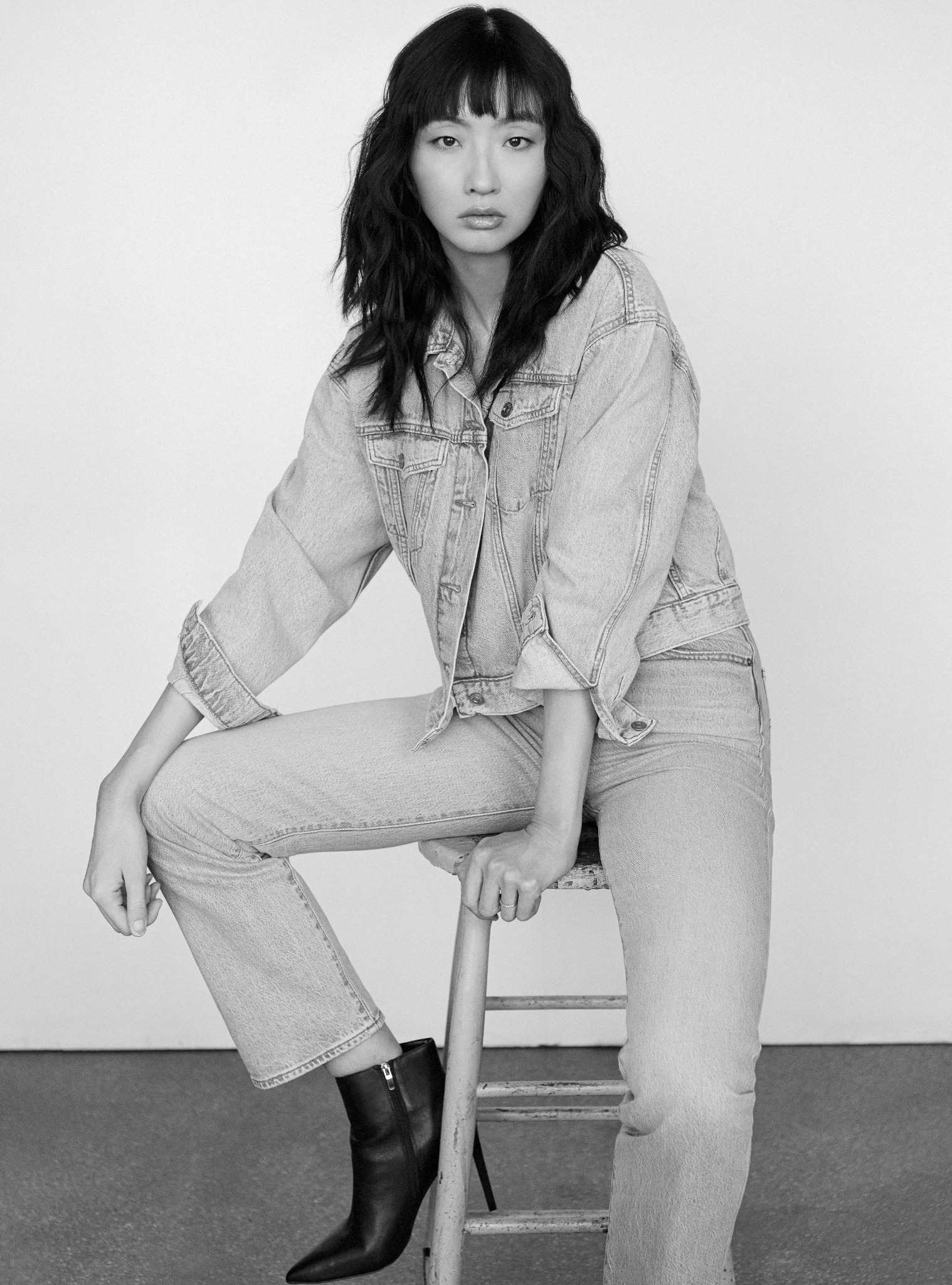 Tian seated in a black-and-white denim editorial